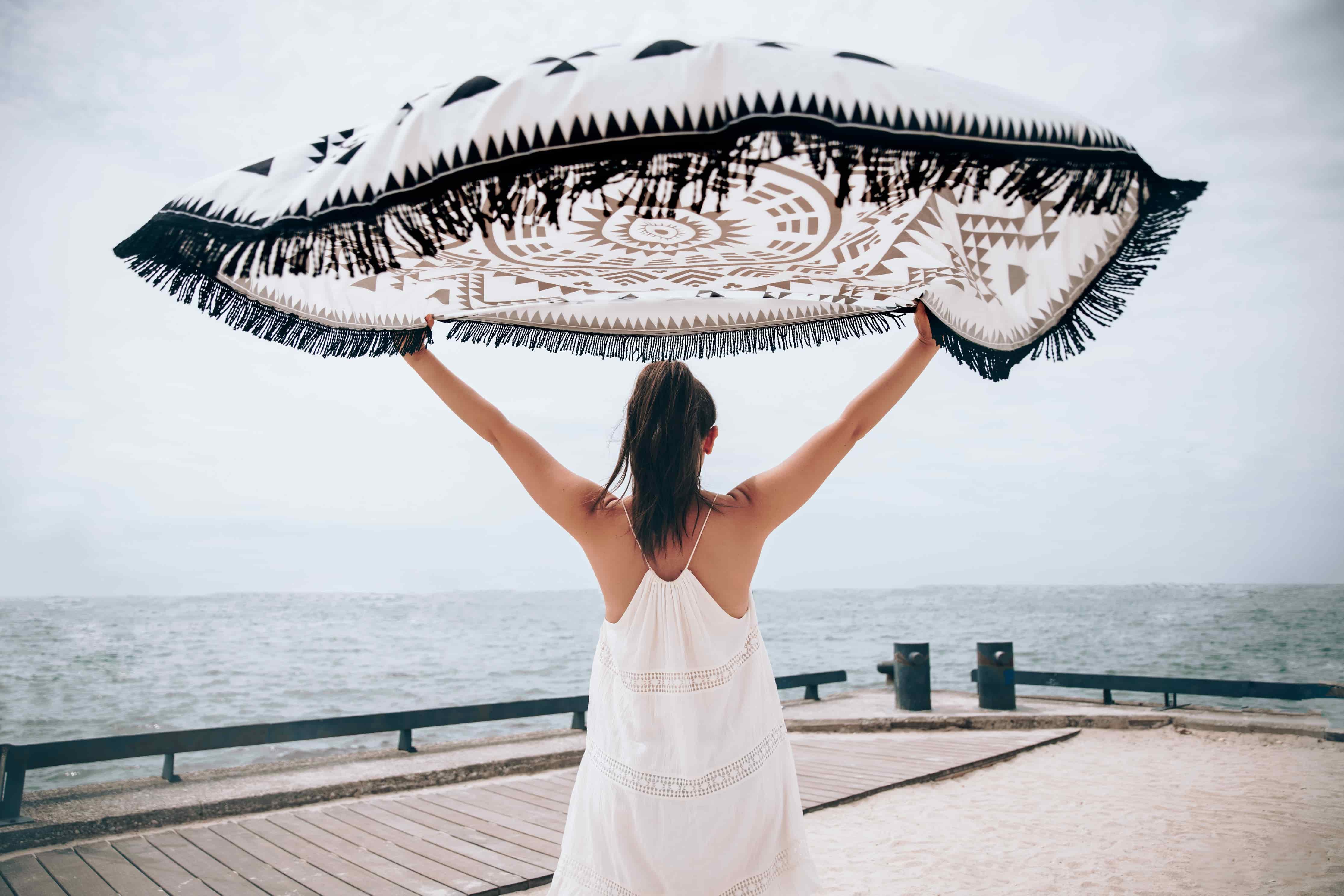 image of woman in white summer dress holding a skarf above herself